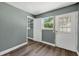 View of a bedroom with laminate flooring, neutral gray paint, and a door to the exterior at 1257 N Pine Hills Rd, Orlando, FL 32808
