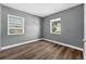 Bedroom featuring two windows, gray walls, and wood-look vinyl floors at 1257 N Pine Hills Rd, Orlando, FL 32808