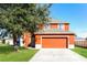 Two-story home with an attached garage, lush green lawn, and mature tree in front at 148 Conch Dr, Kissimmee, FL 34759