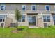 Townhome backyard with green grass, young tree, and sliding glass door at 16390 Bird Of Paradise Ave, Clermont, FL 34714