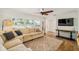 Cozy living room features wood floors, neutral sectional sofa, large windows with plantation shutters, and a ceiling fan at 2114 Geigel Ct, Orlando, FL 32806