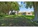 A grassy backyard with mature trees and the back of the property at 21144 Royal St Georges Ln, Leesburg, FL 34748