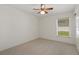 A bedroom with neutral carpet, a ceiling fan, and a window overlooking the yard at 21144 Royal St Georges Ln, Leesburg, FL 34748