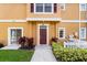 Inviting condo entrance featuring a red door and lush landscaping at 2280 San Vital Dr # 101, Kissimmee, FL 34741