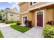 Inviting condo entrance featuring a red door and lush landscaping, adjacent unit visible at 2280 San Vital Dr # 101, Kissimmee, FL 34741