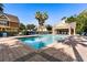 Community pool and sundeck with lounge chairs and lush landscaping and nearby clubhouse on a sunny day at 2280 San Vital Dr # 101, Kissimmee, FL 34741