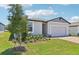 A gray house with fresh green landscaping is equipped with a large two-car garage and dark roof at 2365 White Tail St, Davenport, FL 33837