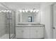 Bright bathroom featuring a glass-enclosed shower and a double vanity with granite countertop at 24401 Sunnys Halo Way, Sorrento, FL 32776