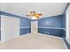 Bedroom with blue accent wall, neutral carpet, ceiling fan, and door to hallway at 2592 Westminster Ter, Oviedo, FL 32765