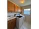 Functional laundry room features wooden cabinets, utility sink, washer and dryer at 3807 Plantation Blvd, Leesburg, FL 34748