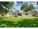 Expansive backyard featuring a lush lawn, mature trees, and a charming white home with a screened-in porch at 4106 Alverado St, Orlando, FL 32812