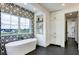 Modern bathroom with soaking tub, patterned accent wall, and custom storage at 4343 Juliana Lake Dr, Auburndale, FL 33823