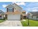 Charming two-story home with a two-car garage, stone accents, manicured lawn, and well-lit driveway at 5365 Rocking Horse Pl, Oviedo, FL 32765