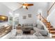 Bright living room featuring high ceilings, a ceiling fan, multiple windows, and two sofas with a staircase nearby at 5365 Rocking Horse Pl, Oviedo, FL 32765