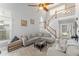 Bright living room featuring high ceilings, a ceiling fan, multiple windows, and two sofas with a staircase nearby at 5365 Rocking Horse Pl, Oviedo, FL 32765