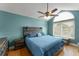 Inviting bedroom featuring a blue quilt, wooden accents, and a window providing natural light at 5365 Rocking Horse Pl, Oviedo, FL 32765