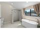 Bathroom featuring soaking tub, walk-in shower with elegant tile surround and a window for natural light at 5420 Lido St, Orlando, FL 32807