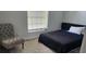 Cozy bedroom with a gray chair, modern rug, and window with blinds for privacy at 6026 Canyon De Chelley Ct, Orlando, FL 32810