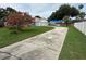 Long driveway leading to a home with a well-maintained lawn and vibrant pink flowering tree at 6026 Canyon De Chelley Ct, Orlando, FL 32810