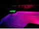 Swimming pool lit with green and pink lighting at night with brick paver trim at 680 Cheoy Lee Cir, Winter Springs, FL 32708