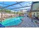 Beautiful screened-in pool with brick pavers, string lights, and lush landscaping, perfect for outdoor relaxation at 680 Cheoy Lee Cir, Winter Springs, FL 32708