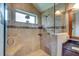 The glass-enclosed shower features neutral tile, a bench, and a window letting in plenty of natural light at 680 Cheoy Lee Cir, Winter Springs, FL 32708