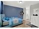 Comfortable bedroom featuring a blue accent wall, wood flooring, and view to the en-suite bathroom at 8713 Iron Mountain Trl, Windermere, FL 34786