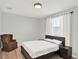 Bedroom featuring wood floors, a dark bed frame, and a cozy brown armchair at 8713 Iron Mountain Trl, Windermere, FL 34786