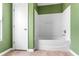 Bathroom with green walls featuring a tub and shower combination and white door at 1033 Sabine Pl, Kissimmee, FL 34759