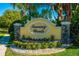 Community sign with 'Tuscany Woods' in a yellow oval, framed by stone pillars and lush landscaping at 113 San Mardeen Ct, Daytona Beach, FL 32117