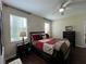 Cozy bedroom featuring stylish bedding, two windows offering natural light, and dark wood floors at 12728 Boggy Pointe Dr, Orlando, FL 32824
