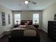 Relaxing primary bedroom features a ceiling fan, bedside tables with lamps, and two large windows at 12728 Boggy Pointe Dr, Orlando, FL 32824