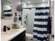 Modern bathroom with black hardware, marble countertops, and a striped shower curtain at 1310 Briarwood Ave, Deltona, FL 32725