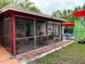 Enclosed back porch offering additional space for relaxation with comfortable wicker seating, potted plants, and brick pavers at 1310 Briarwood Ave, Deltona, FL 32725