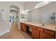 Bathroom with dual sinks, wood cabinets, a long vanity, and a large mirror at 13838 Bluebird Park Rd, Windermere, FL 34786
