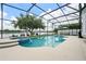 Screened pool and patio area overlook a serene lake, offering a tranquil outdoor living space at 13838 Bluebird Park Rd, Windermere, FL 34786