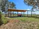Open-air shed with a tractor, offering functional outdoor storage on a spacious, well-maintained lawn at 14243 County Road 450, Umatilla, FL 32784