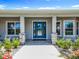 Welcoming front porch with stone columns, manicured lawn, and a blue front door at 14243 County Road 450, Umatilla, FL 32784