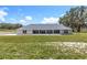 Beautiful rear exterior view featuring a covered patio and a sprawling, lush green lawn at 14243 County Road 450, Umatilla, FL 32784