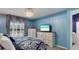 Well-lit bedroom with blue walls, dark-patterned bedding, dressers, and decorative curtains at 1614 Oak Hill Trl, Kissimmee, FL 34747