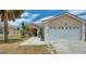 Charming single-story home with an attached two-car garage, palm tree, and landscaping at 1614 Oak Hill Trl, Kissimmee, FL 34747