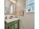 Elegant powder room features a modern green vanity, gold fixtures, and a stylish framed mirror at 183 Longview Ave, Kissimmee, FL 34747