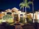 Nighttime exterior view of a stunning home with a manicured lawn, fountain, and palm trees at 204 Quail Trail Ct, Lake Mary, FL 32746