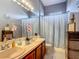 Bright bathroom featuring a double vanity, updated fixtures, and a shower with blue patterned curtain at 2530 The Oaks Blvd, Kissimmee, FL 34746