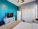 Well-lit bedroom with a vibrant teal accent wall, light-colored dresser, closet, and comfortable bed at 2530 The Oaks Blvd, Kissimmee, FL 34746