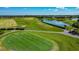 Scenic golf course view featuring a pristine green, sand trap, picturesque lake, and golf cart path at 2530 The Oaks Blvd, Kissimmee, FL 34746