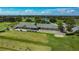 Aerial view of a meticulously maintained golf course featuring a clubhouse, manicured lawns, and a serene lake at 2530 The Oaks Blvd, Kissimmee, FL 34746