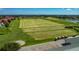 Expansive golf course with a driving range and golf cart parking, set against a backdrop of residential homes and a lake at 2530 The Oaks Blvd, Kissimmee, FL 34746