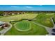 A well-kept golf course green and driving range near red-roofed condos on a sunny day at 2530 The Oaks Blvd, Kissimmee, FL 34746