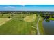 Scenic aerial view of lush golf course with palm trees, a walking path, and a beautiful lake in a vibrant community at 2530 The Oaks Blvd, Kissimmee, FL 34746